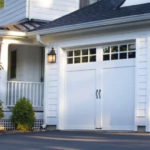 House with two white steel carriage house style garage doors