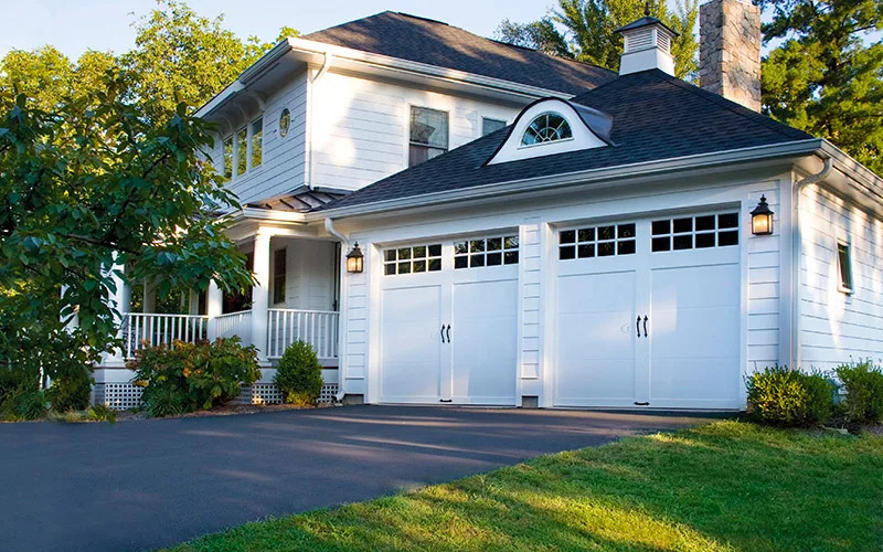 House with two white steel carriage house style garage doors