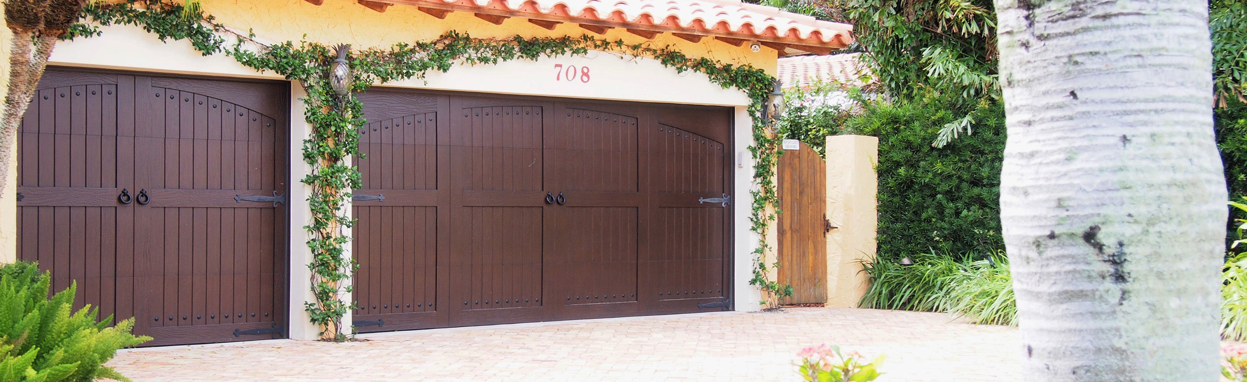 Home with brown single-car and double-car Eden Coast series garage doors
